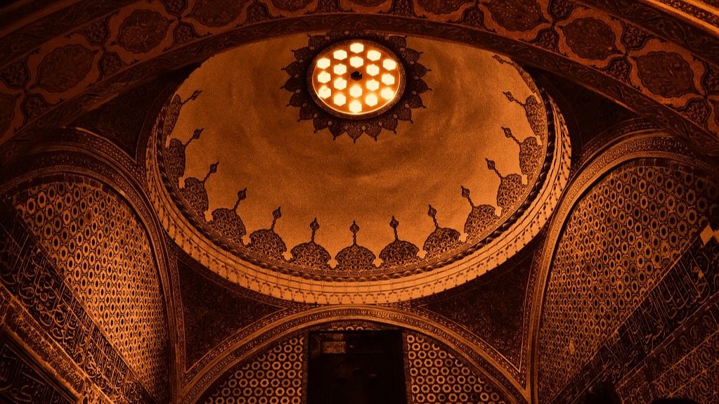 An ornate domed ceiling lit from a central skylight, showing layered architectural structure