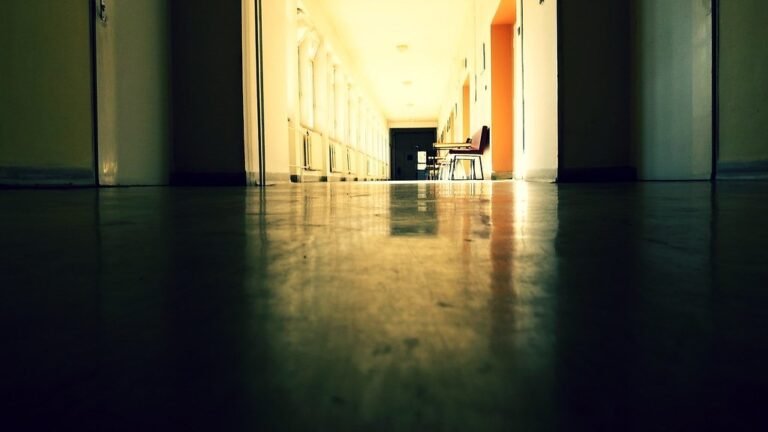 A hospital corridor receding toward warm light at the far end